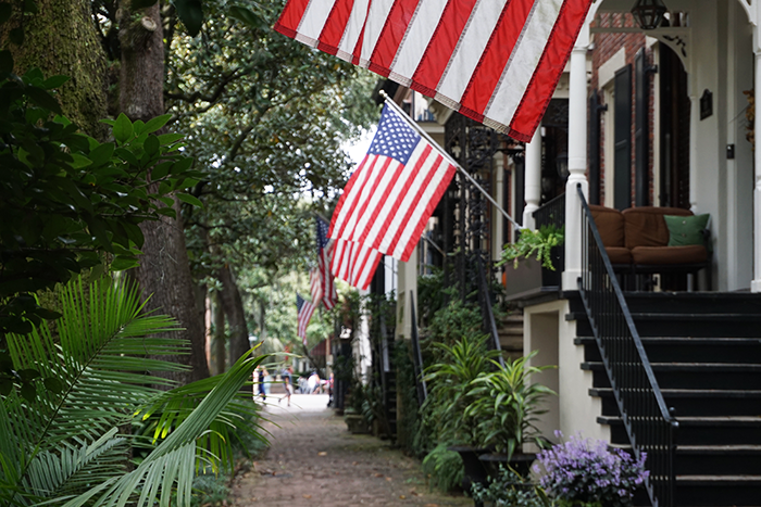 flags waving from old homes on brick sidewalk